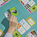 Hand holding a card above a collection of colorful game cards on a teal surface